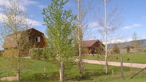A rural setting with two wooden houses, a fenced area, and a mountain in the background. - 2BR Pet Friendly Darby Barn (Driggs)