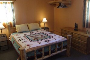 Ein Zimmer mit einem Bett, einem Nachttisch, einer Kommode und einer Lampe.
