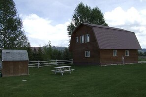 Rustic barn with multiple windows and a picket fence.