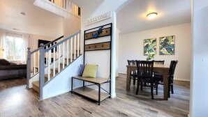 A staircase with a 'WELCOME' sign, a dining area with wooden chairs and a table, and a living room with a sofa and a window. - 5 Minute Drive to Downtown Bend, Dog Friendly (Bend)