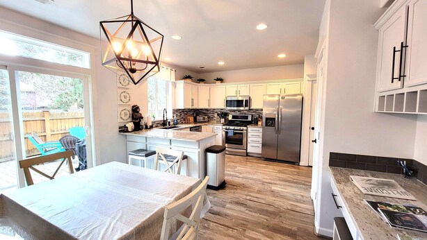 A modern kitchen with white cabinets, a central island, stainless steel appliances, and a geometric pendant light. - 5 Minute Drive to Downtown Bend, Dog Friendly (Bend)