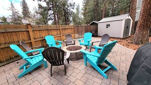 A patio with turquoise Adirondack chairs arranged around a circular stone fire pit. - 5 Minute Drive to Downtown Bend, Dog Friendly (Bend)