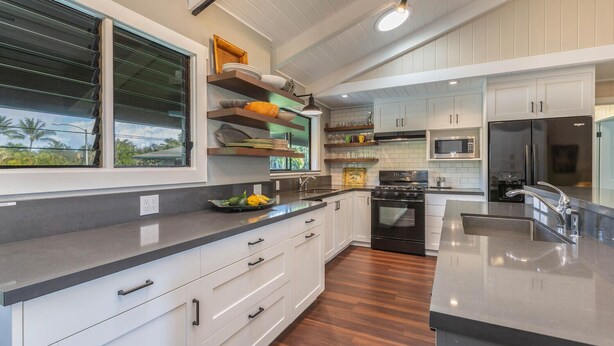 A modern kitchen with white cabinetry, a stainless steel sink, and a built-in oven.