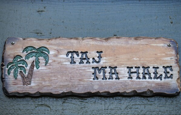 A wooden sign with palm tree carvings and the text "TAJ MA HALE". - Charming and Immaculate - Walkable to Beach and Town - Sleeps 10 (Hanalei)