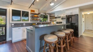 A modern kitchen with a central island, bar stools, and a built-in refrigerator.