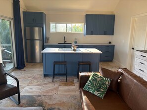 A modern kitchen with blue cabinets, a stainless steel refrigerator, and a central island with stools.