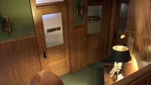 Una escalera de madera con barandilla acolchada, un banco de madera y una lámpara fijada a la pared.