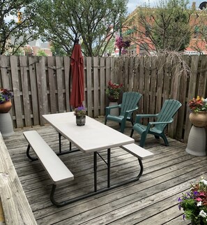 Une terrasse en bois avec une table de pique-nique et deux chaises vertes.