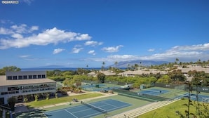 Un complexe de courts de tennis comprenant plusieurs terrains, entouré de bâtiments résidentiels et d’une végétation luxuriante.