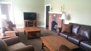 Ein Wohnzimmer mit Kamin, Fernseher und einer Couch.