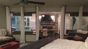 Une chambre à coucher avec un lit, un bureau et une chaise. On peut voir un balcon avec une table et des chaises.