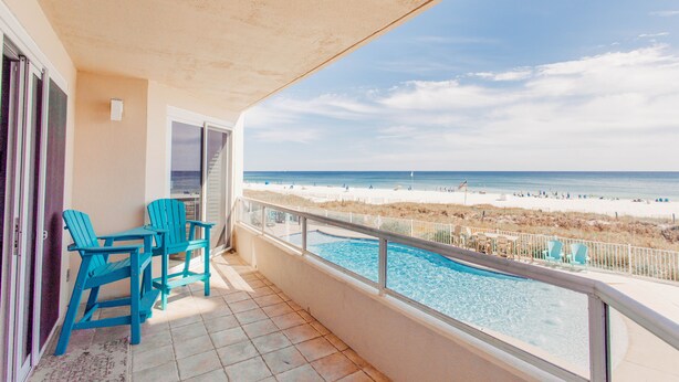 Varanda com piscina, vista para a praia e duas cadeiras.