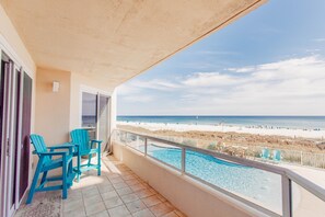 Ein Balkon mit Pool, Strandblick und zwei Stühlen.