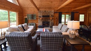 Un intérieur de chalet chaleureux avec deux canapés, une cheminée et un mur en pierre.