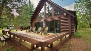 Une cabane en rondins dotée d’une terrasse, de meubles d’extérieur et d’une porte-fenêtre coulissante.