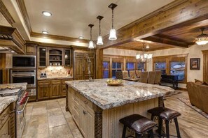 A spacious kitchen with granite countertops, a large island, and a bar area.