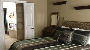 A bedroom with a large bed, wooden flooring, a white door, a mirror, and a dresser. - Gorgeous Home In Upscale Neighborhood - Room For The Whole Family 4 bedrooms! (Pawhuska)