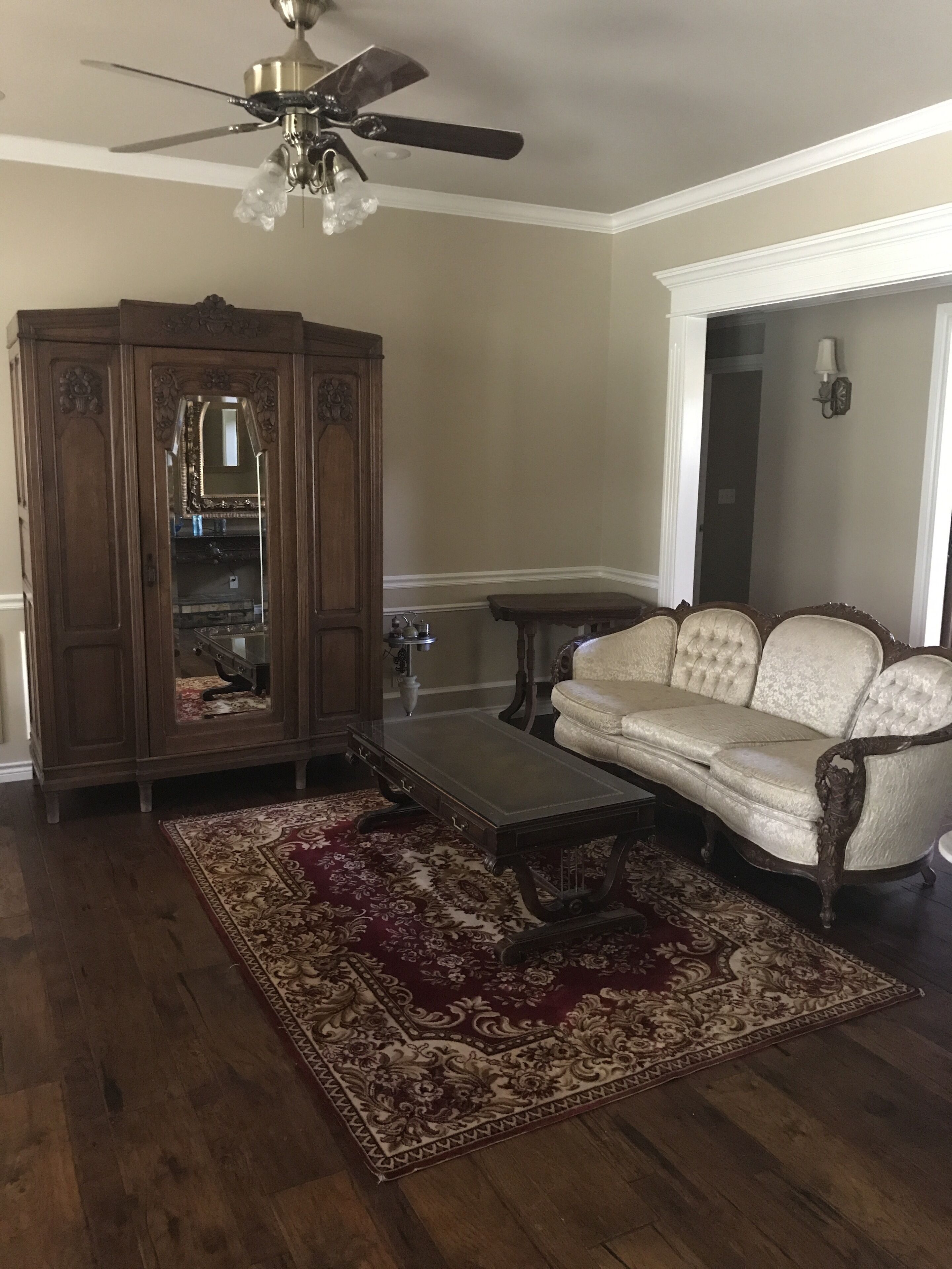 Una sala de estar con un aparador de madera, un sofá, una mesa de centro y un ventilador de techo.