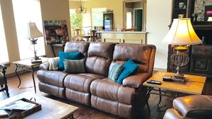 A brown leather sofa with blue and striped cushions, a wooden coffee table, a lamp, and a television on a wooden stand. - Gorgeous Home In Upscale Neighborhood - Room For The Whole Family 4 bedrooms! (Pawhuska)