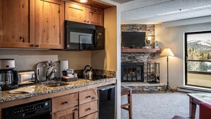 A modern kitchen with wooden cabinets, granite countertops, a built-in microwave, and a dishwasher. - 9 Hot Tubs! Ski-In/Ski-out Suite (Breckenridge)