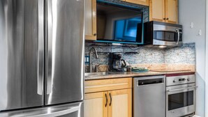 Una cocina moderna con electrodomésticos de acero inoxidable, gabinetes de madera y salpicadero de azulejos, además de un microondas integrado.