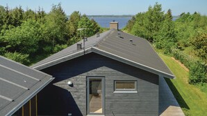 A modern house with a sloped roof, a chimney, and a view of a lake.