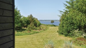 A view of a well-maintained lawn leading to a body of water, surrounded by dense greenery and trees.