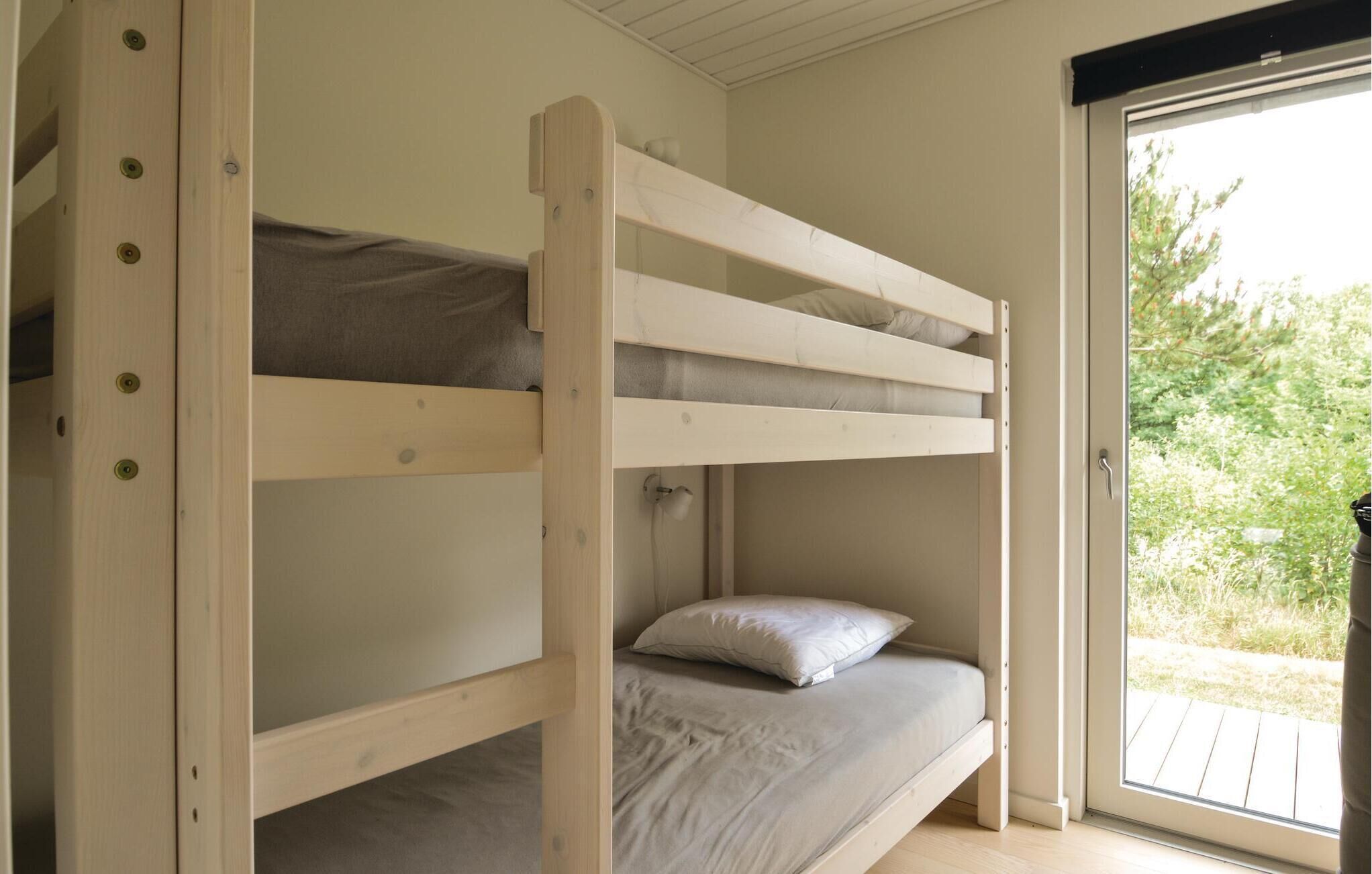 A bunk bed with a wooden frame, a grey mattress, and a white pillow.