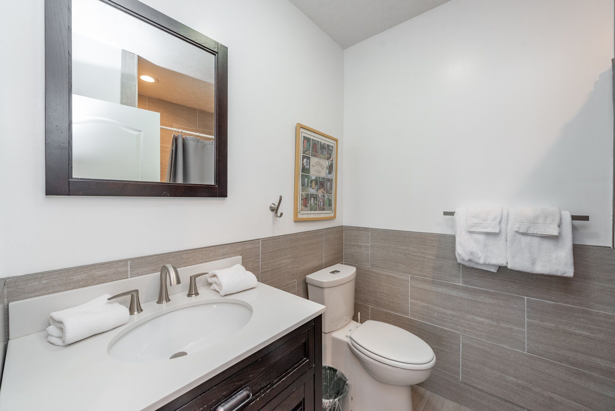 A modern bathroom with a large sink, a toilet, and a mirror.
