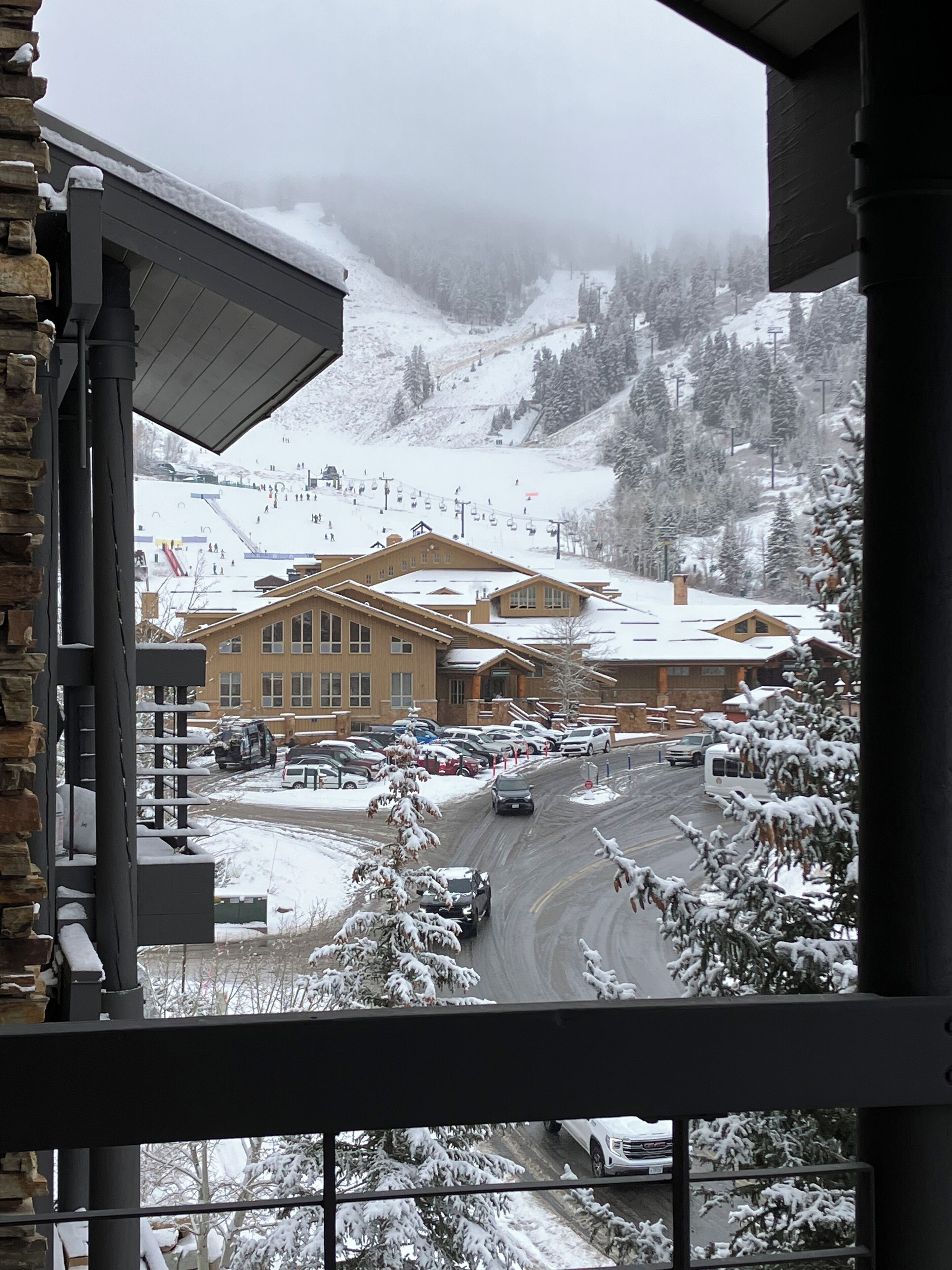 Ein Blick auf ein Gebäude mit einer Seilbahn im Hintergrund, umgeben von schneebedeckten Bäumen und einer verschneiten Landschaft.