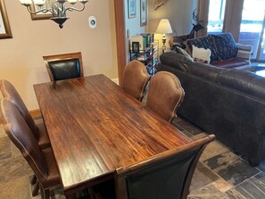 A dining area with a wooden table and leather chairs, a sofa, and a lamp.