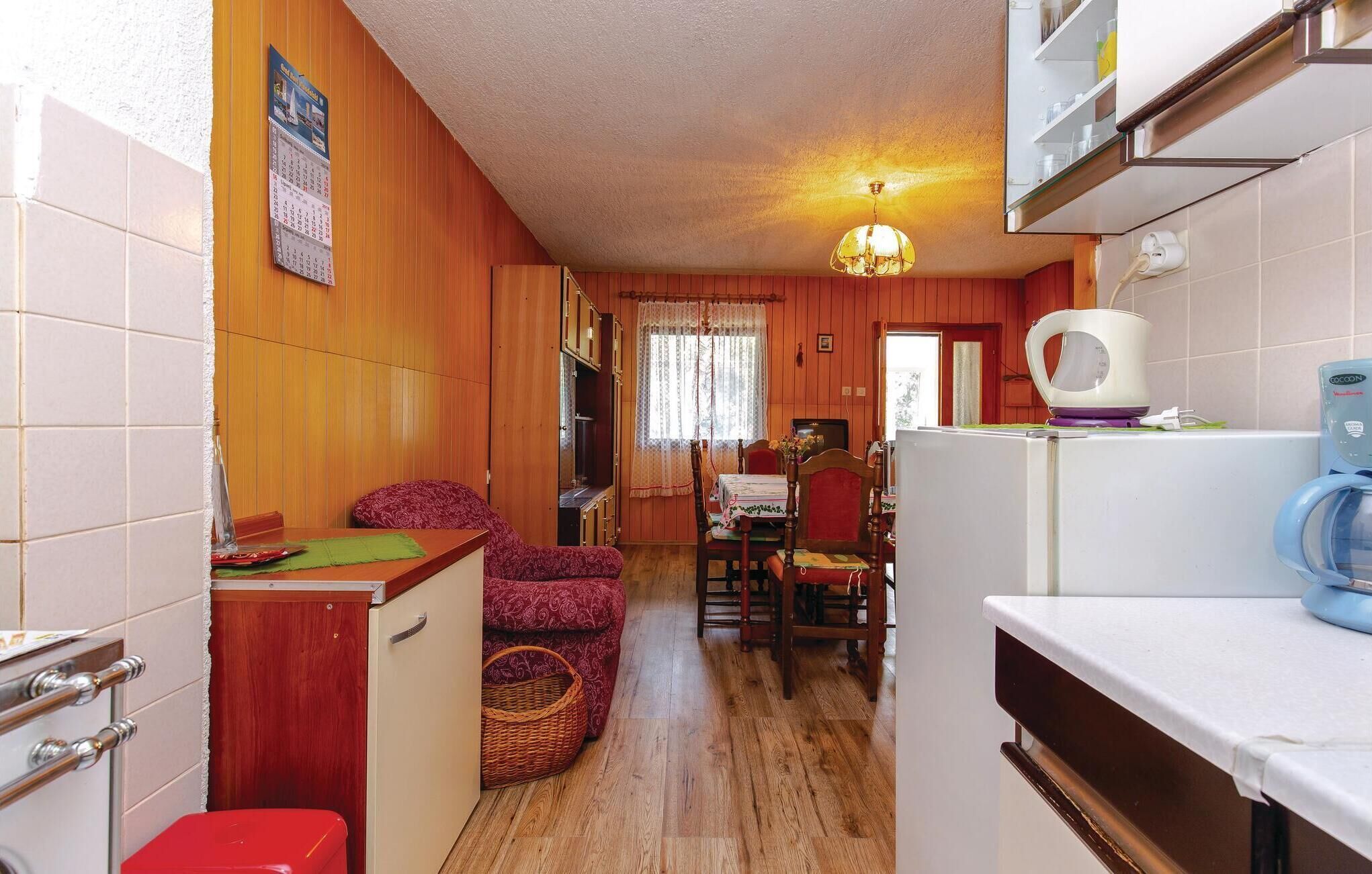 Eine kleine Küche mit Holzwänden, einem Essbereich mit Tisch und Stühlen, einem Kühlschrank und einer Waschmaschine.