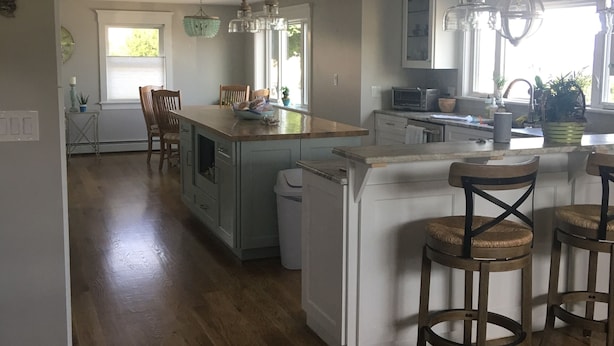 A spacious kitchen with a central island, wooden bar stools, and pendant lighting. - Oasis by the sea in Nahant  (Nahant)