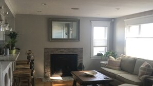 A spacious living room with a fireplace, a sofa, and a dog. - Oasis by the sea in Nahant  (Nahant)