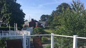 A deck with two lounge chairs and a small table, surrounded by a white fence and greenery. - Oasis by the sea in Nahant  (Nahant)