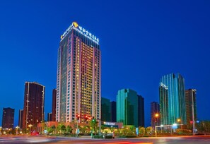 A high-rise hotel with multiple floors, a prominent sign at the top, and a well-lit facade. - Empark Grand Hotel Hangzhou Bay Ningbo (Ningbo)