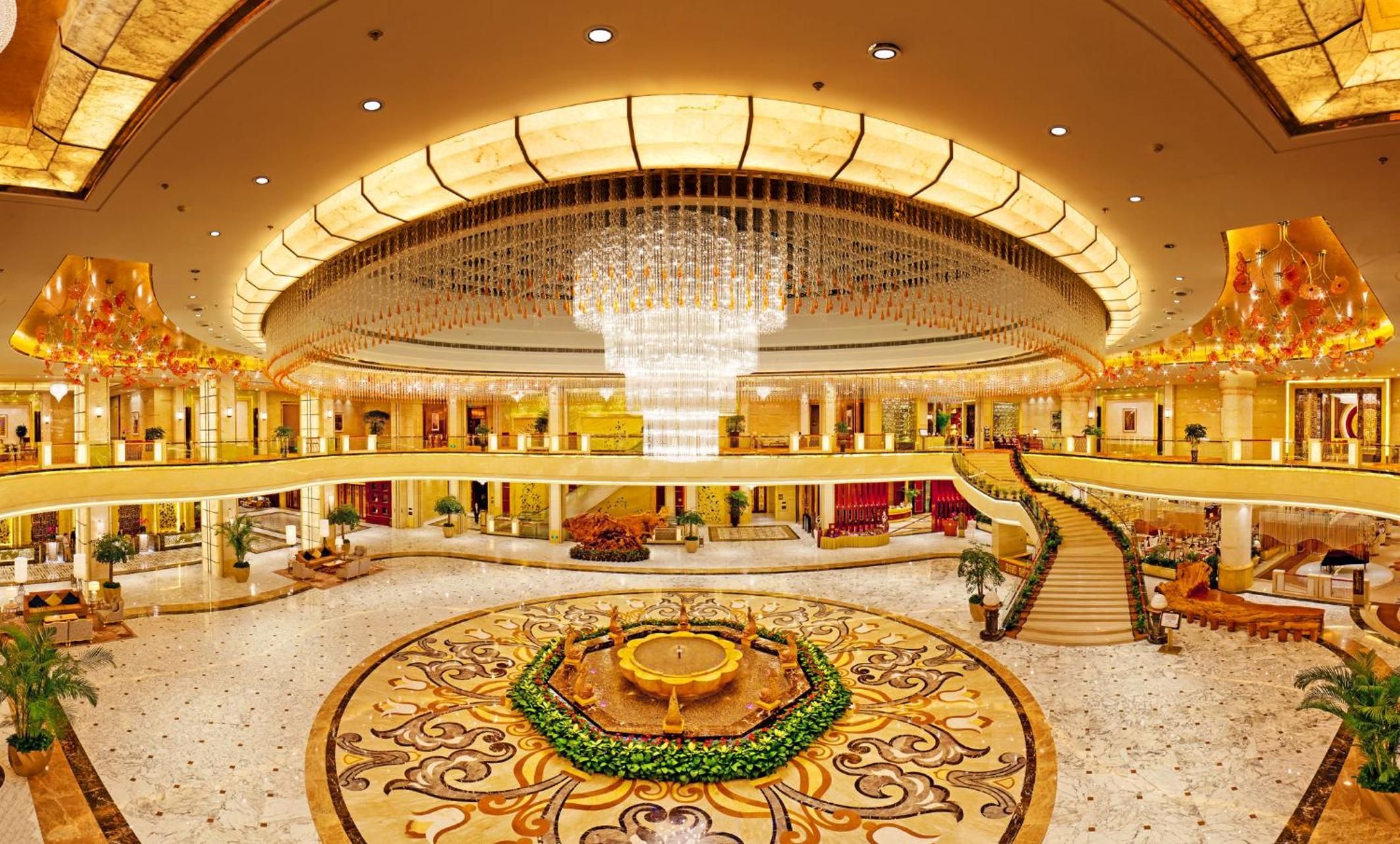 A multi-level atrium with a central fountain, multiple balconies, and a grand chandelier.