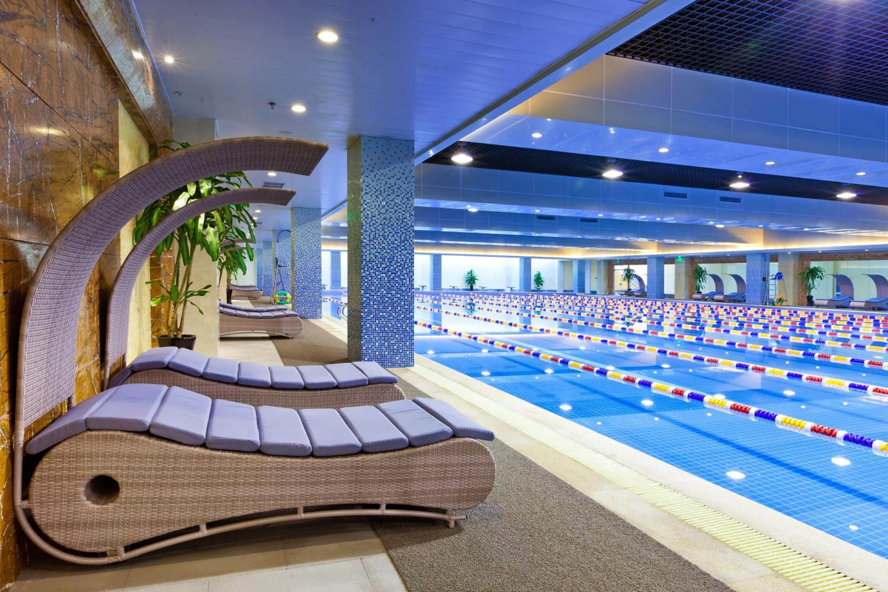 A swimming pool area with lounge chairs and a tiled wall.