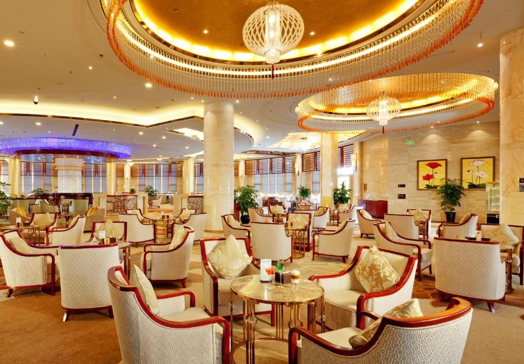Un vestíbulo de hotel con mesas redondas, sillas y un gran candelabro.