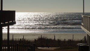 Blick auf einen Strand mit einer Holzlattenveranda und einem Gebäude mit Geländer.