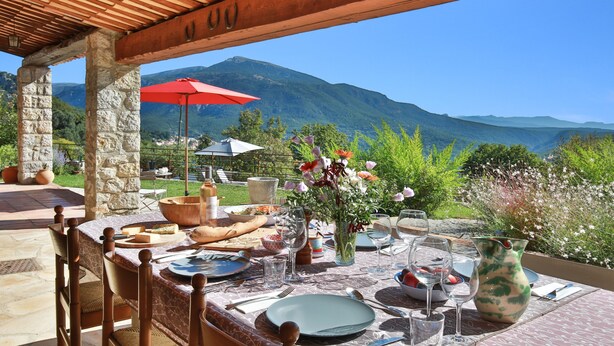 An outdoor dining area with stone pillars, a wooden pergola, and a table set for a meal. - Provencal villa located in serene setting with panoramic views, sleeps 12 (Le Bar-sur-Loup)