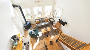 A spacious living area with a sofa, chairs, a wooden table, and a fireplace. - Group Getaway on a Private Peninsula (Grand Rapids)