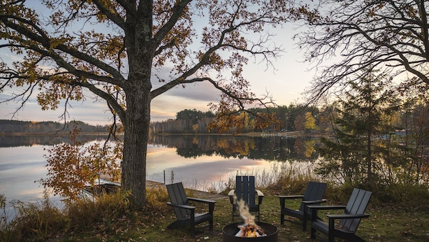 A lakeside setting with a fire pit and three Adirondack chairs. - Group Getaway on a Private Peninsula (Grand Rapids)