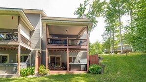 Ein zweistöckiges Haus mit überdachter Terrasse, Whirlpool und Deck.
