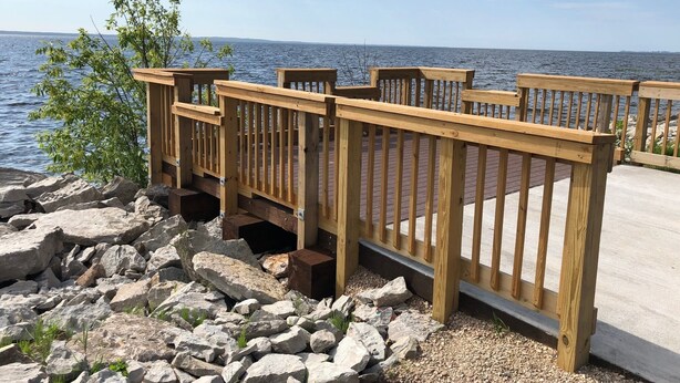 A wooden deck with railings overlooking a body of water.