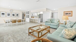 A modern living room with a sofa, coffee table, and dining area with chairs and a table.