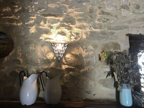Experience the warmth of a traditional setting with a stone wall backdrop, a unique sconce, and decorative ceramics.