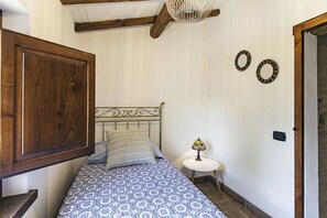 Cozy bedroom with a single bed, wooden beams, and a large wardrobe.