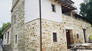 A stone building with a balcony and a small table with chairs outside. - Agriturismo la Palazzetta di Assisi (Assisi)
