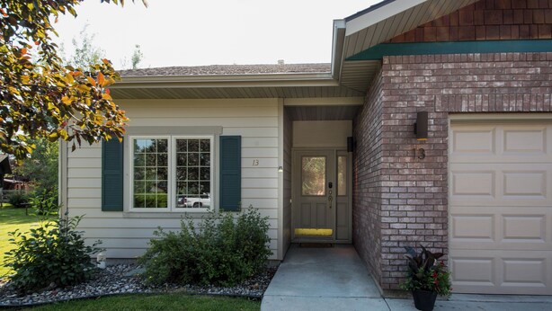 Une maison d’habitation avec un garage, une porte d’entrée et un petit jardin.